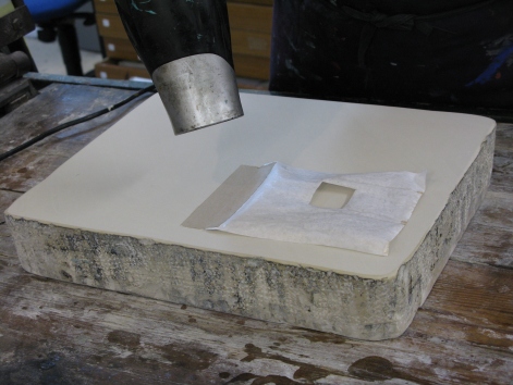 The drawing on transfer paper is taped to the stone using gum strip. Depending on how thin the paper is it may be necessary to run through the press a few times at this stage to flatten the paper, (ensuring a protective piece of polythene is laid between the stone and paper so that the drawing is not transferred yet).